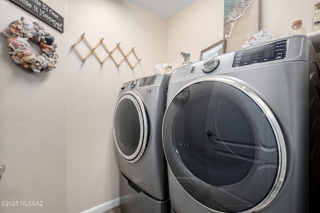 washroom with laundry area, washing machine and dryer, and baseboards