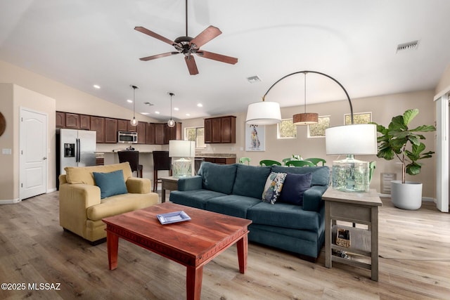 living room featuring light wood-style flooring, visible vents, vaulted ceiling, and recessed lighting