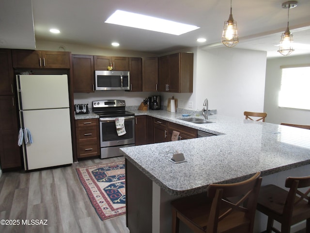 kitchen with appliances with stainless steel finishes, a sink, a peninsula, and a breakfast bar area