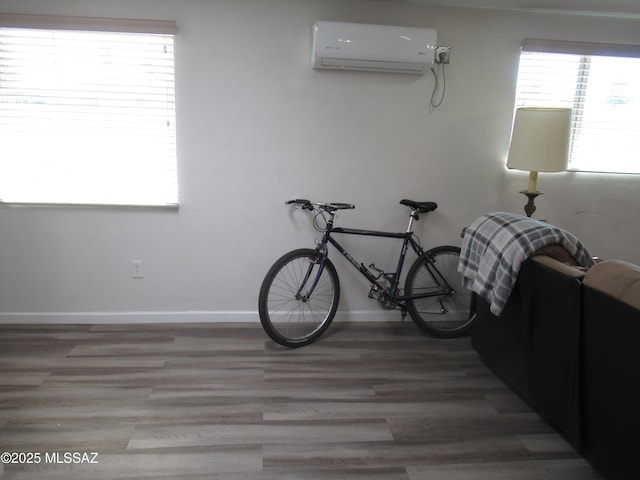 misc room with light wood-style floors, a wall mounted AC, and baseboards