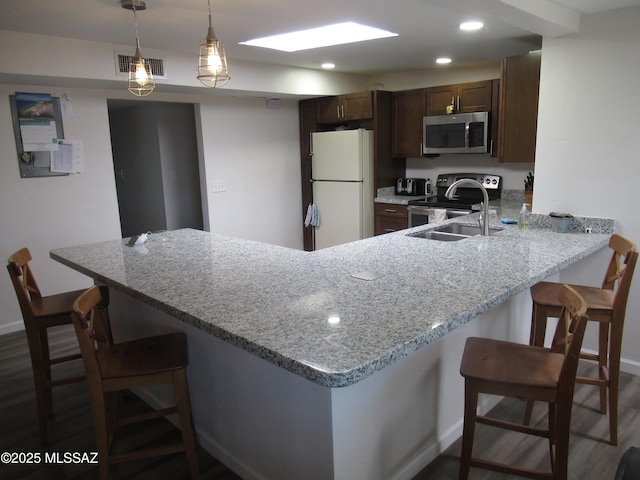 kitchen with stainless steel appliances, visible vents, a sink, a peninsula, and a kitchen breakfast bar