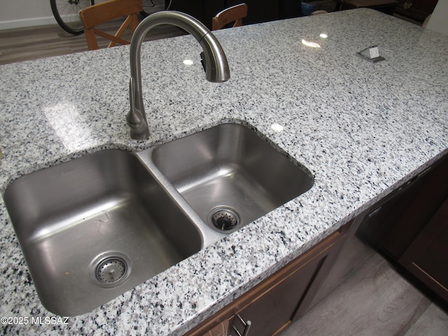 interior details with light stone counters, a sink, dishwashing machine, and wood finished floors