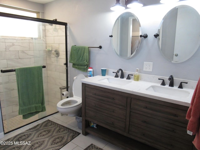 full bathroom with double vanity, a stall shower, a sink, and toilet