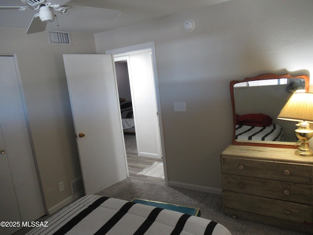 carpeted bedroom with a ceiling fan, visible vents, and baseboards