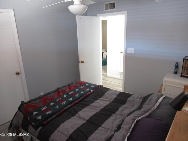 bedroom with ceiling fan, wood finished floors, and visible vents