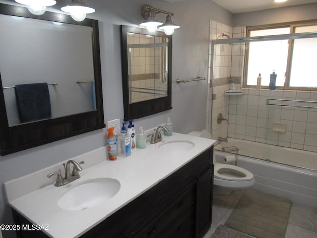 bathroom featuring double vanity, a sink, toilet, and bath / shower combo with glass door