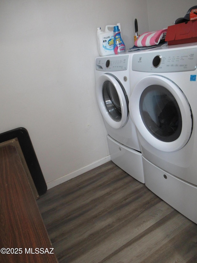 clothes washing area with laundry area, baseboards, wood finished floors, and washing machine and clothes dryer