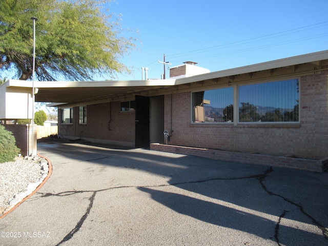 ranch-style house with a carport, brick siding, and driveway