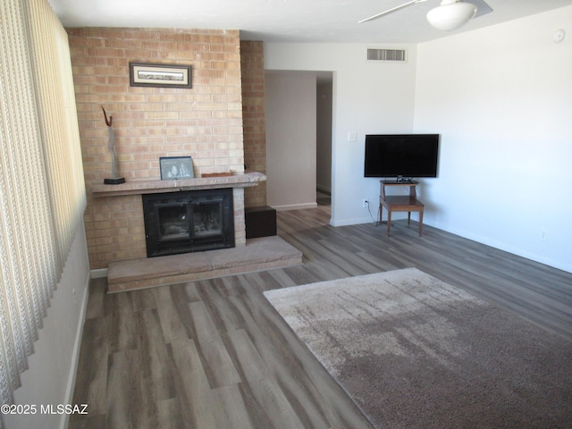 unfurnished living room with visible vents, a fireplace, baseboards, and wood finished floors