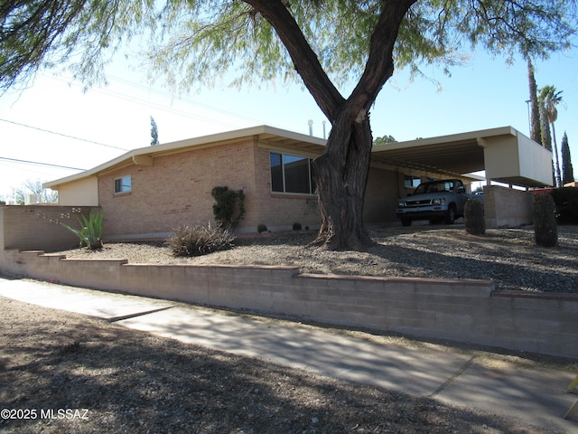 view of side of property featuring a carport, brick siding, and driveway