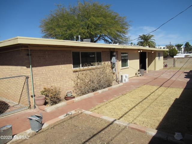 view of front facade with a patio, brick siding, ac unit, and fence