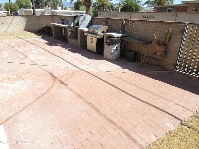 view of patio with area for grilling, fence, and a grill