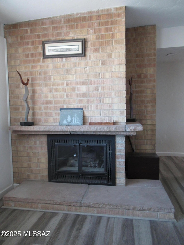 details with a fireplace with raised hearth, baseboards, and wood finished floors