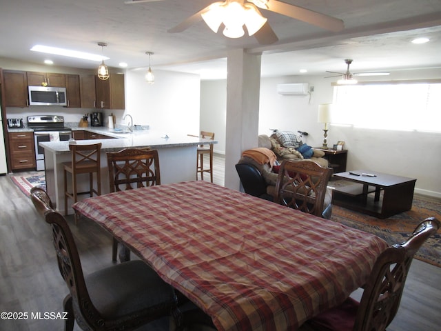 dining area with a ceiling fan, a wall mounted air conditioner, and wood finished floors