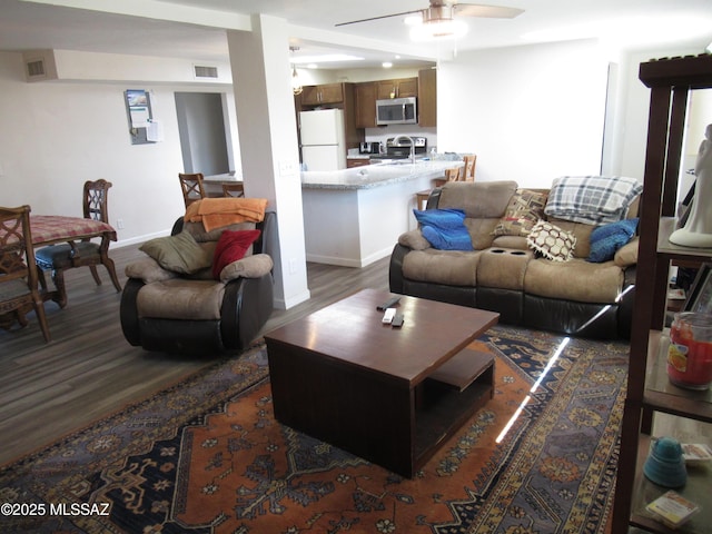 living area featuring visible vents, dark wood finished floors, and baseboards