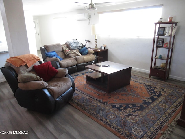 living room with ceiling fan, an AC wall unit, wood finished floors, and baseboards