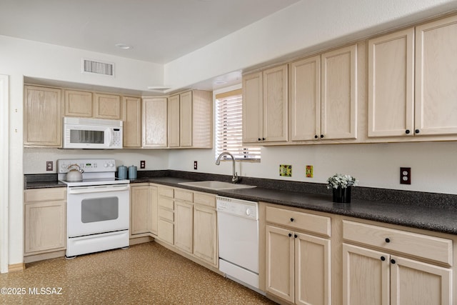 kitchen with dark countertops, visible vents, light brown cabinetry, a sink, and white appliances