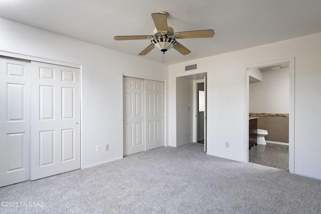 unfurnished bedroom featuring visible vents, ensuite bathroom, multiple closets, and light colored carpet