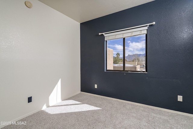 carpeted empty room featuring baseboards