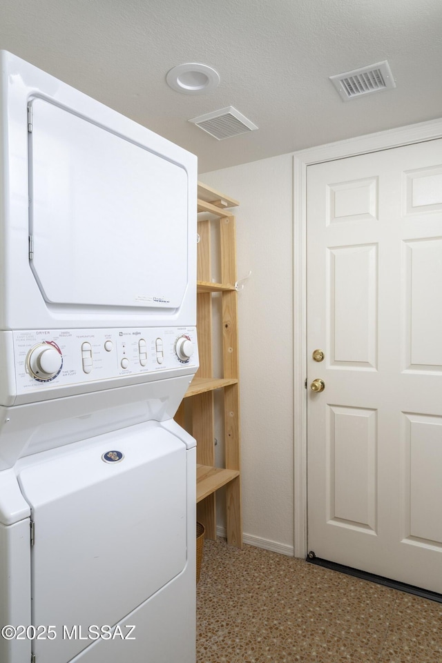 clothes washing area featuring laundry area, visible vents, and stacked washer and dryer