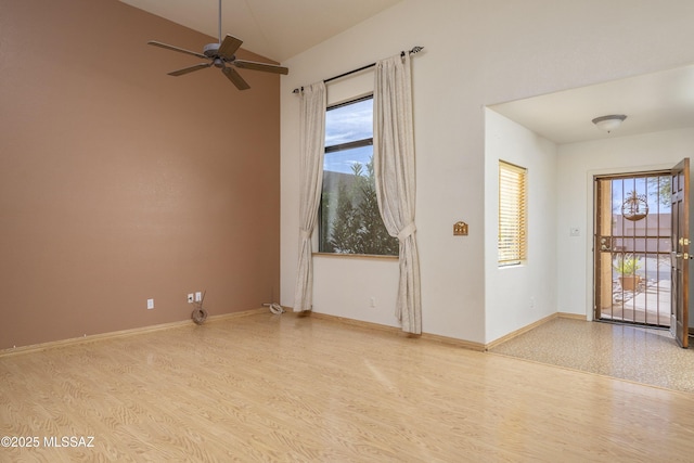 spare room featuring a healthy amount of sunlight, light wood-style flooring, baseboards, and vaulted ceiling