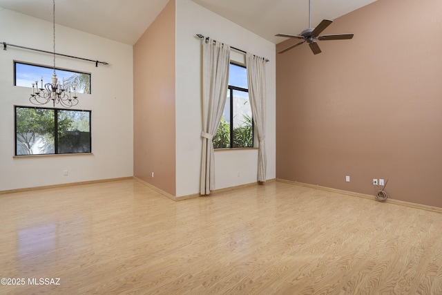 empty room with high vaulted ceiling, light wood-type flooring, baseboards, and ceiling fan with notable chandelier