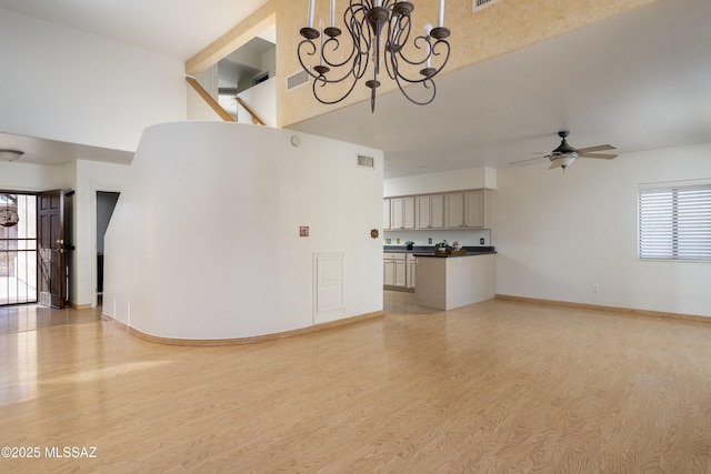 interior space with light wood-type flooring, baseboards, visible vents, and ceiling fan with notable chandelier