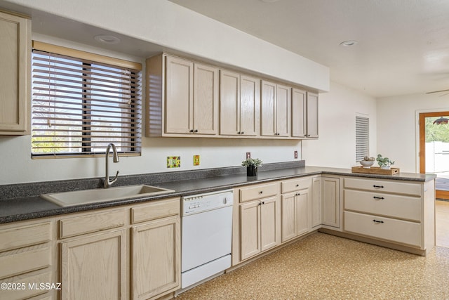 kitchen featuring dark countertops, white dishwasher, a peninsula, and a sink