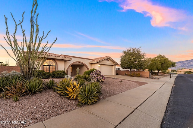 view of front of property featuring a garage, a tiled roof, concrete driveway, and stucco siding