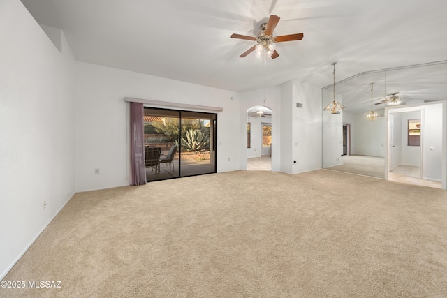 carpeted empty room with a ceiling fan, arched walkways, and vaulted ceiling