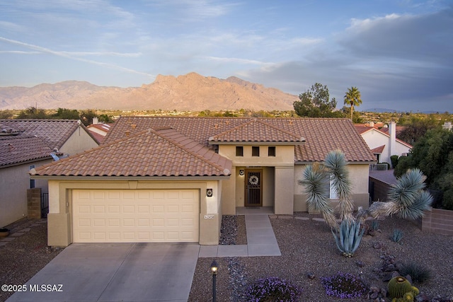 mediterranean / spanish-style home with driveway, a mountain view, a tiled roof, and stucco siding