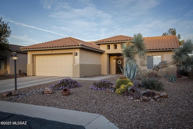 mediterranean / spanish home with concrete driveway, a tile roof, an attached garage, and stucco siding