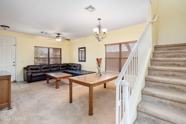 living area featuring a healthy amount of sunlight, stairway, visible vents, and light colored carpet