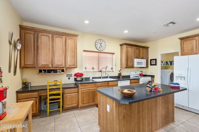 kitchen with white appliances, visible vents, dark countertops, a sink, and light tile patterned flooring