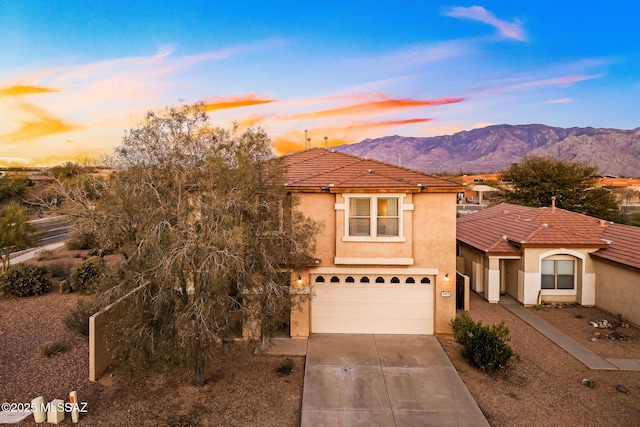 view of front of property featuring a tile roof, stucco siding, concrete driveway, a mountain view, and a garage