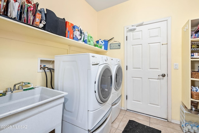 laundry area featuring laundry area, light tile patterned floors, washer and clothes dryer, and a sink