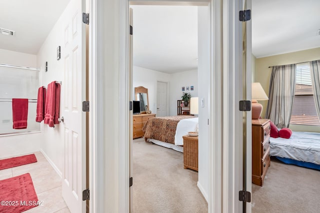 corridor featuring light carpet, light tile patterned floors, baseboards, and visible vents