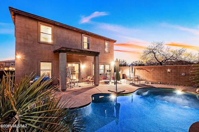 pool at dusk featuring a patio area, a fenced backyard, and a fenced in pool