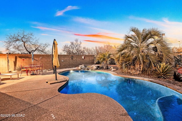 pool at dusk featuring a fenced backyard, a fenced in pool, and a patio