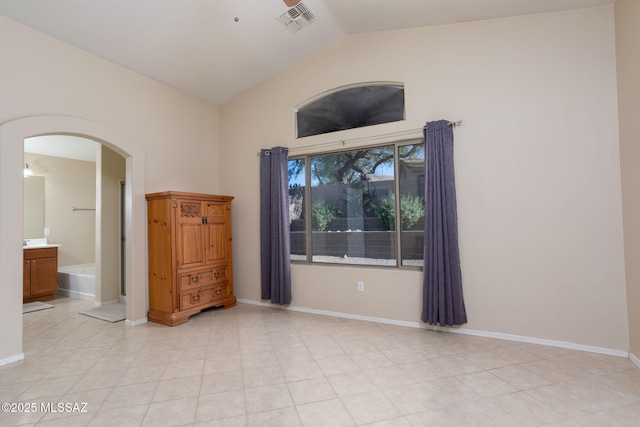 unfurnished room with arched walkways, light tile patterned floors, lofted ceiling, visible vents, and baseboards