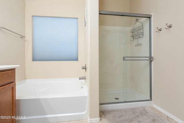 bathroom with vanity, baseboards, a shower stall, a bath, and tile patterned floors