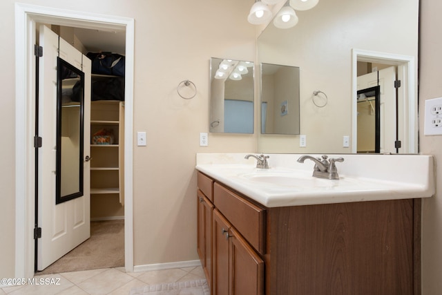 bathroom with double vanity, tile patterned flooring, baseboards, and a sink