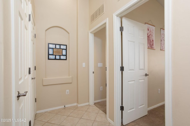 hallway with visible vents, baseboards, and light tile patterned floors