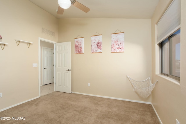 carpeted empty room featuring visible vents, vaulted ceiling, baseboards, and ceiling fan