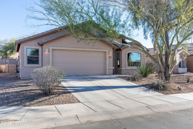 view of front of house with a garage, driveway, fence, and stucco siding