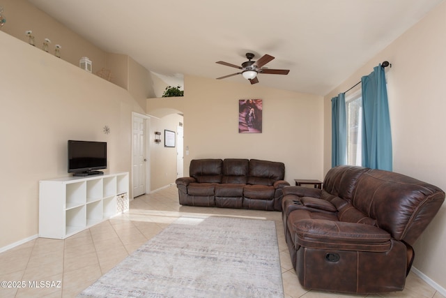 living room with baseboards, arched walkways, a ceiling fan, tile patterned floors, and vaulted ceiling