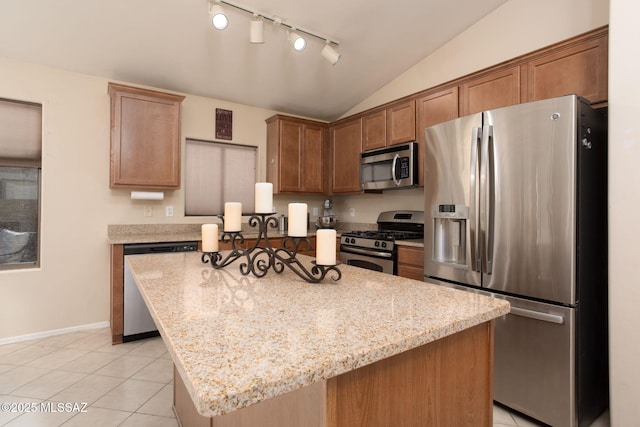 kitchen with a center island, light tile patterned floors, stainless steel appliances, lofted ceiling, and light stone countertops