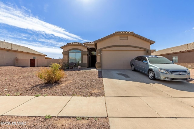 mediterranean / spanish house featuring driveway, a garage, a tile roof, fence, and stucco siding