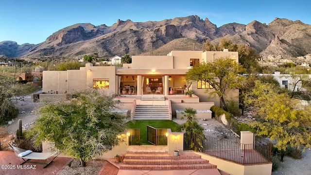 view of front of property with stairs, a mountain view, fence, and stucco siding