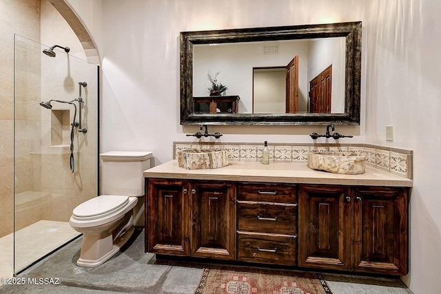 bathroom with toilet, visible vents, tiled shower, and vanity